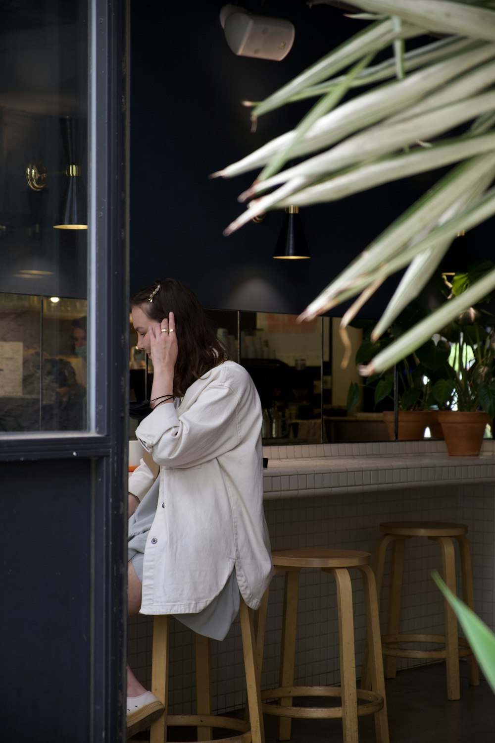 woman in white coat standing near glass window