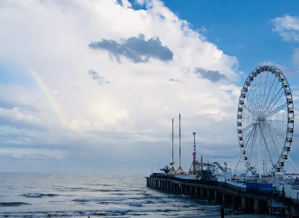 ruota panoramica vicino allo specchio d'acqua sotto il cielo nuvoloso durante il giorno