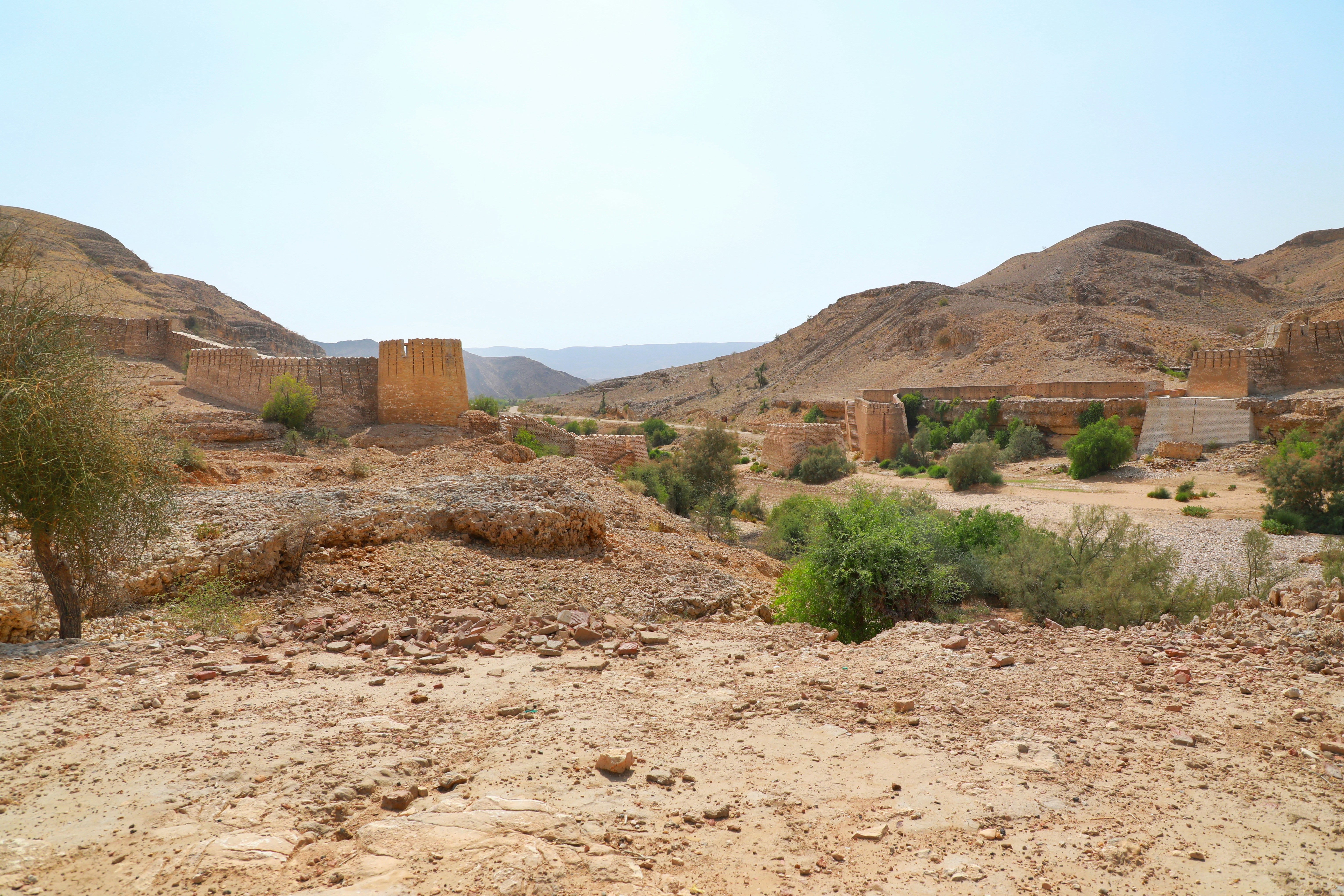 Ancient sandstone fortress rising from the Omani desert landscape under a warm golden sky