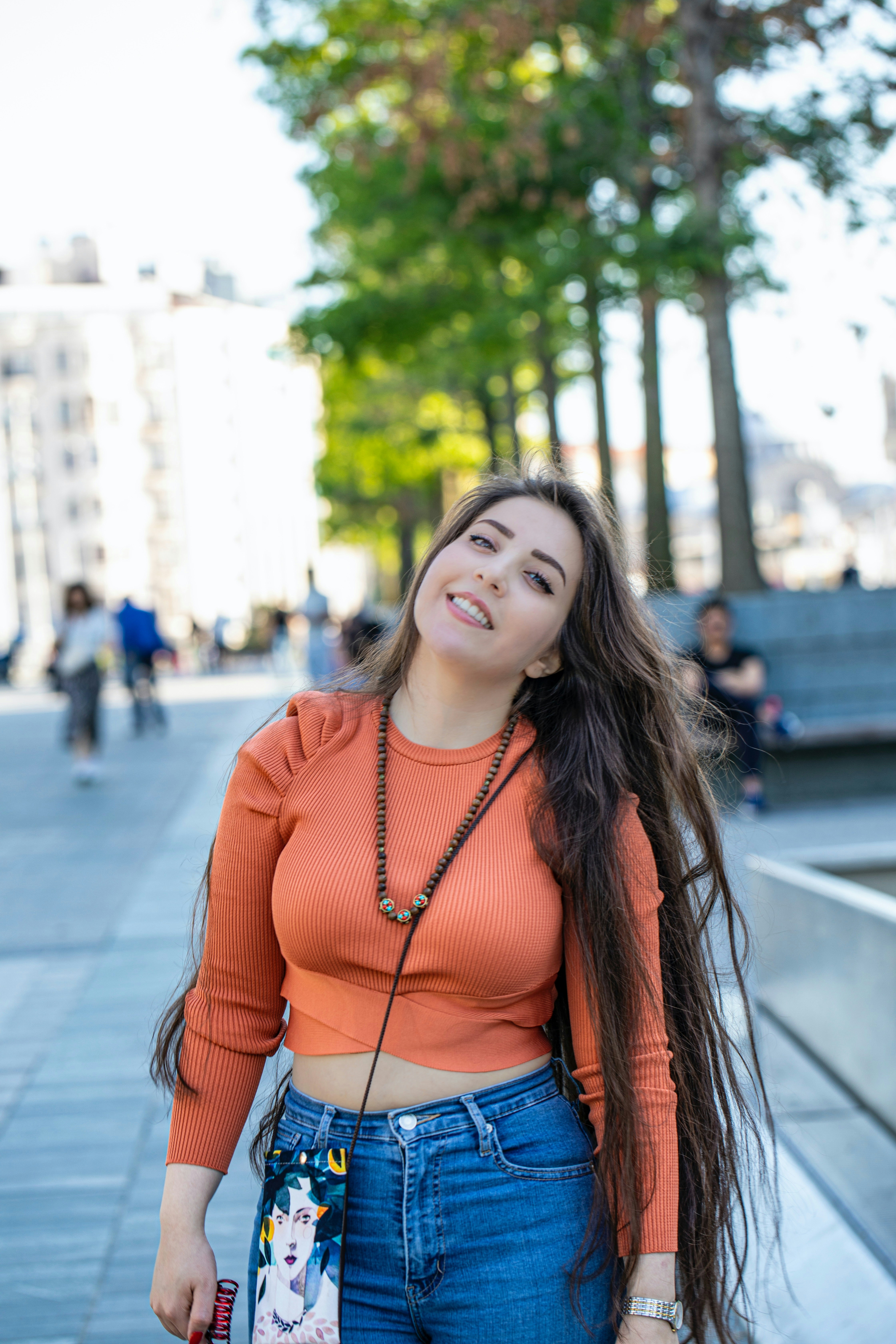 woman in red and black striped long sleeve shirt standing on sidewalk during daytime