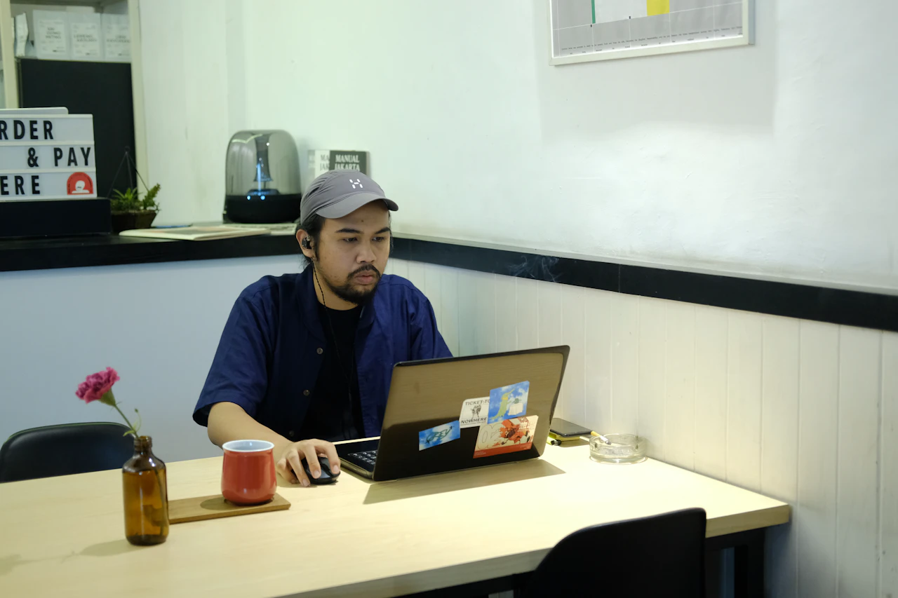 Backpacker reviewing work exchange opportunities on a laptop at a shared hostel table