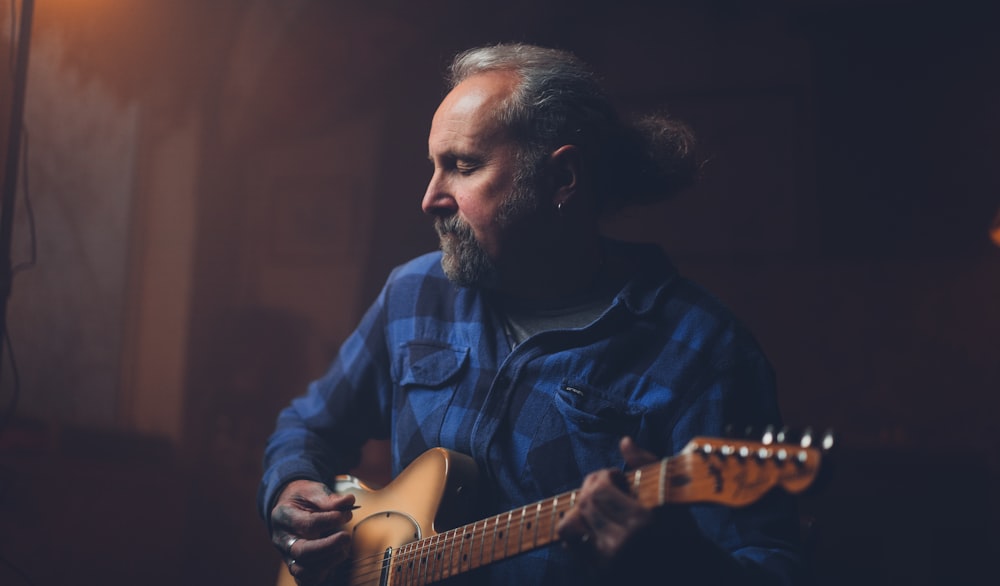 man in blue dress shirt playing electric guitar