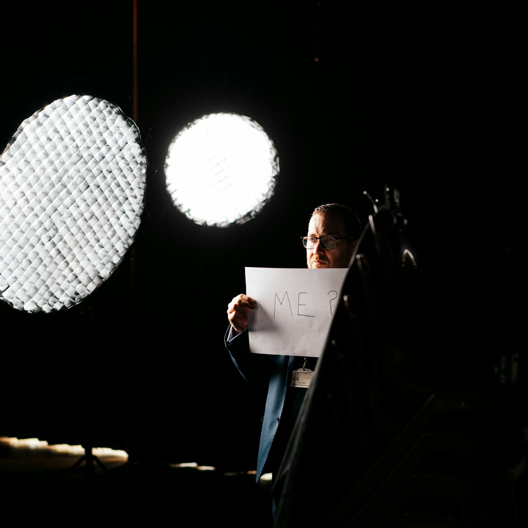 man in black suit jacket holding white paper