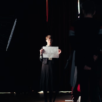 man in black suit holding white paper