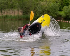 man in red shirt riding yellow surfboard on water during daytime