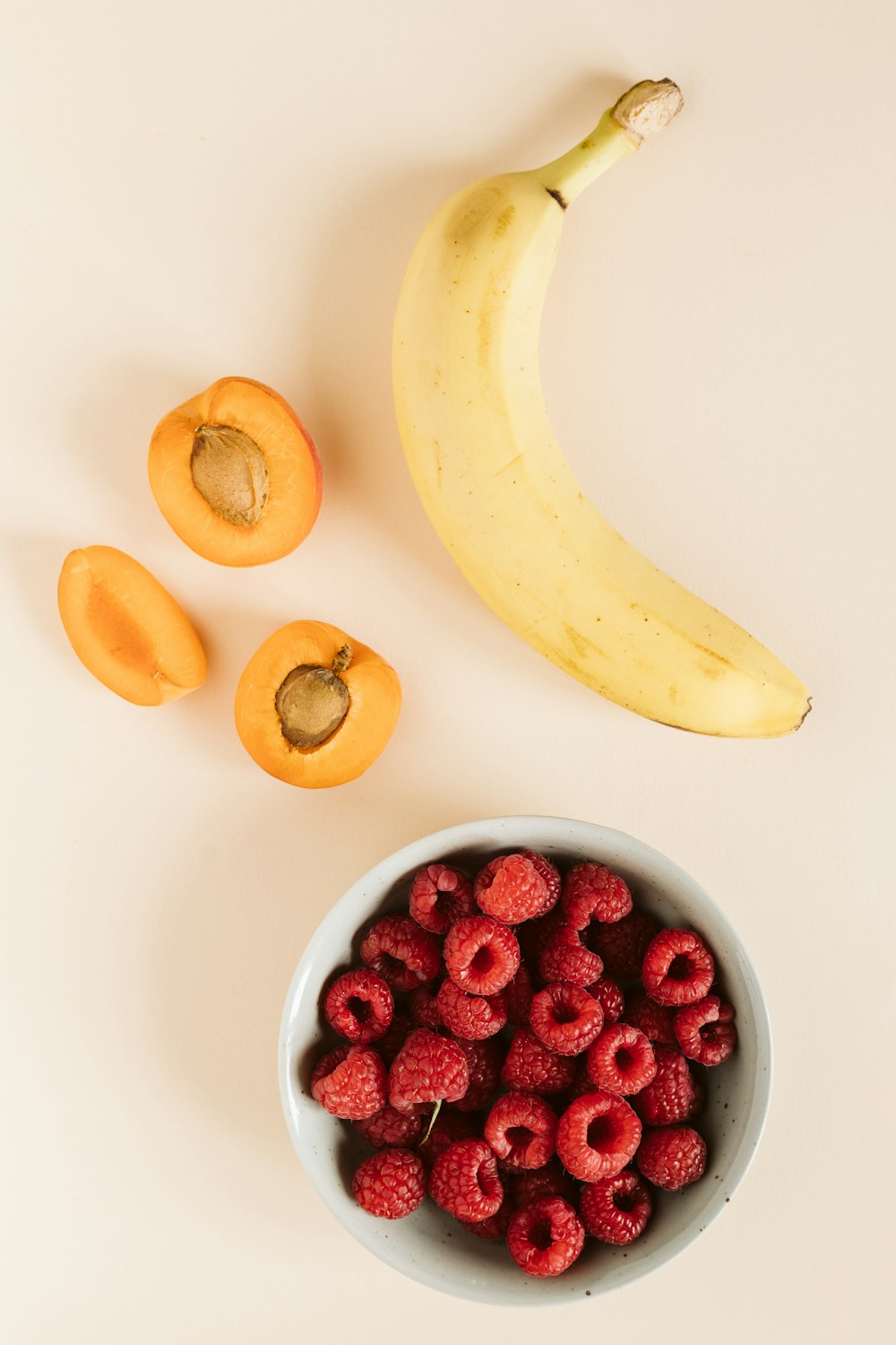 yellow banana and red round fruits on white table