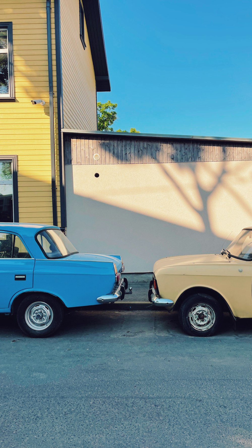 blue and white vintage car parked beside white concrete building during daytime