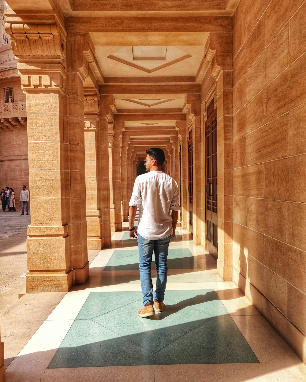 man in white dress shirt and blue denim jeans standing on hallway