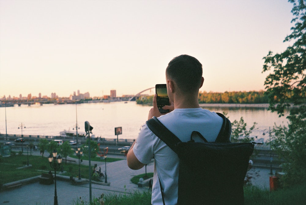 man in white shirt holding black smartphone