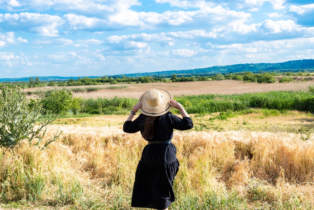 person in black jacket and black pants standing on brown grass field under blue sky during