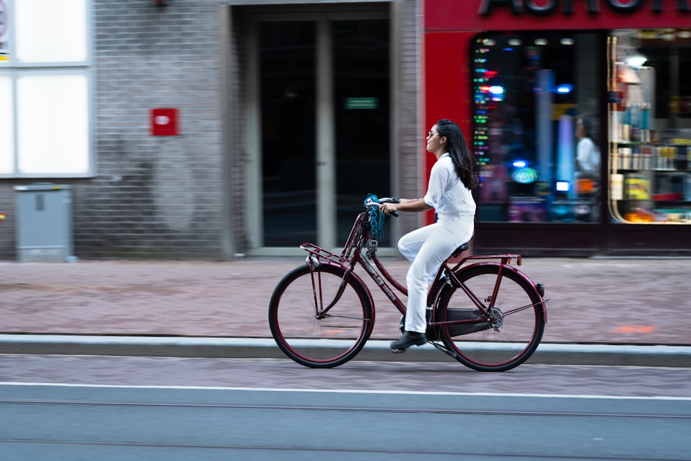 흰색 긴 소매 셔츠와 흰색 바지를 입은 여자 검은 도시 자전거를 타고