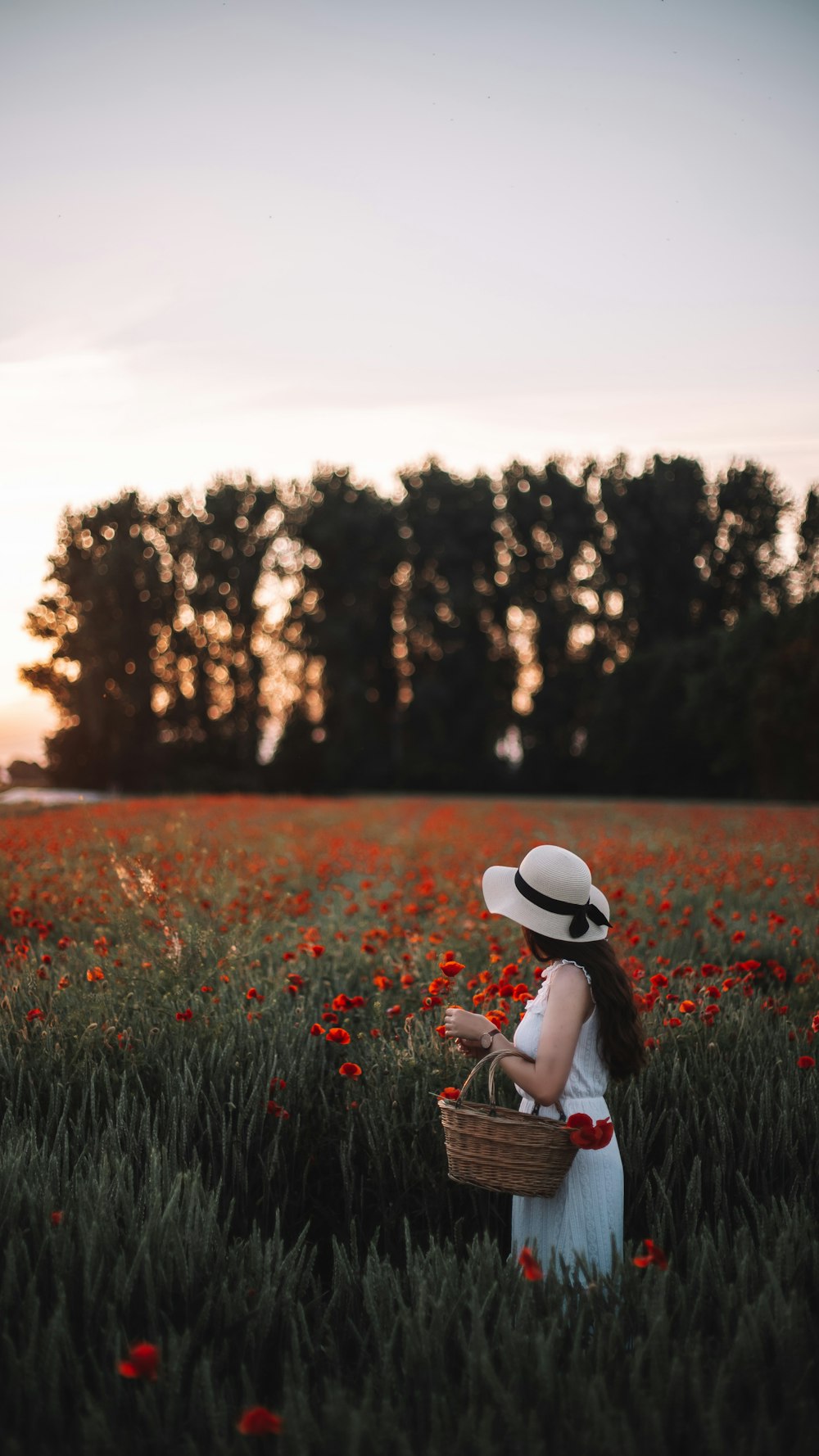 woman in white hat sitting on grass field during daytime