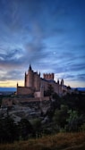 A serene view of Spøttrup Castle surrounded by its deep medieval moats under a soft sunset.