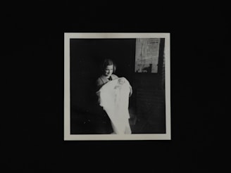 An Indian mother gently holding her smiling baby wrapped in a soft pastel blanket, surrounded by cozy nursery fairy lights.