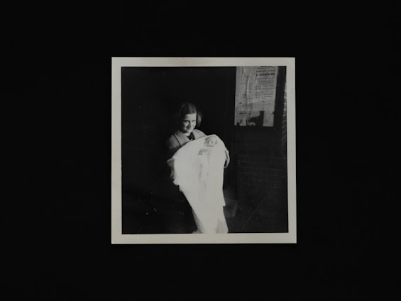 A smiling Indian mother gently holding her baby wrapped in a soft pastel blanket with fairy lights glowing softly in the background.