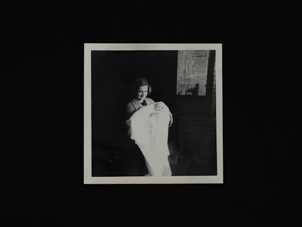 A smiling young mother holding her baby wrapped in a soft mint green blanket.