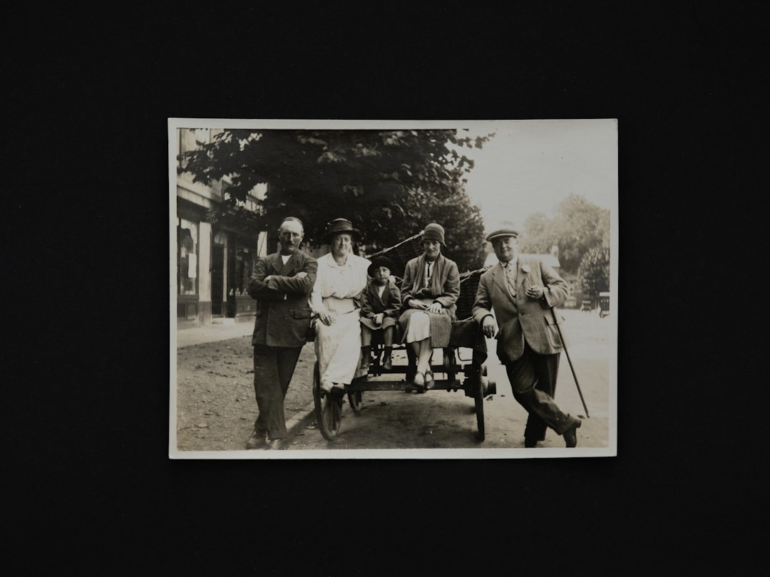 grayscale photo of 4 men standing near trees