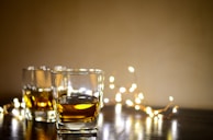 clear shot glass with yellow liquid on brown wooden table