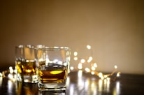 clear shot glass with yellow liquid on brown wooden table
