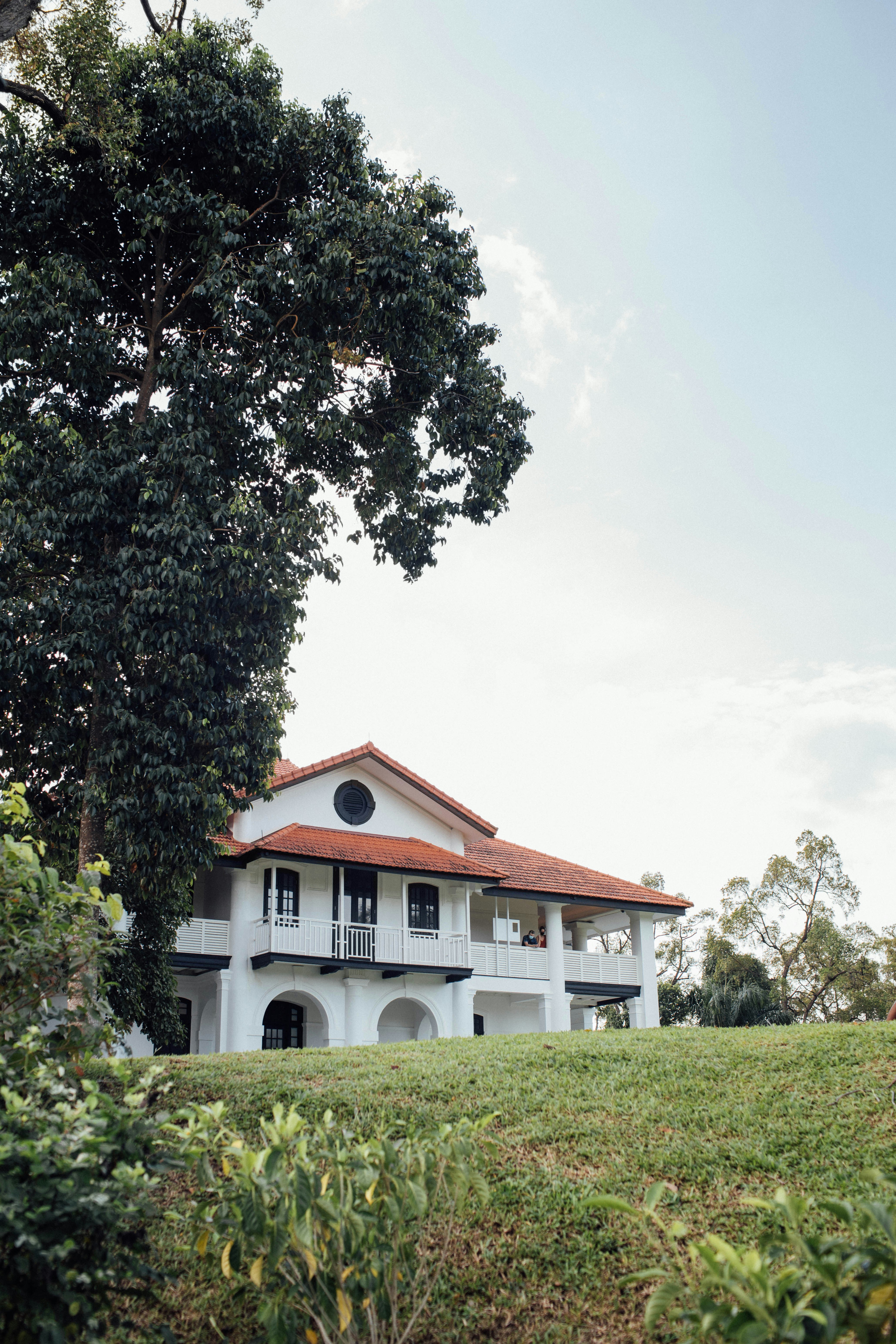 white and brown house near green tree under white clouds during daytime