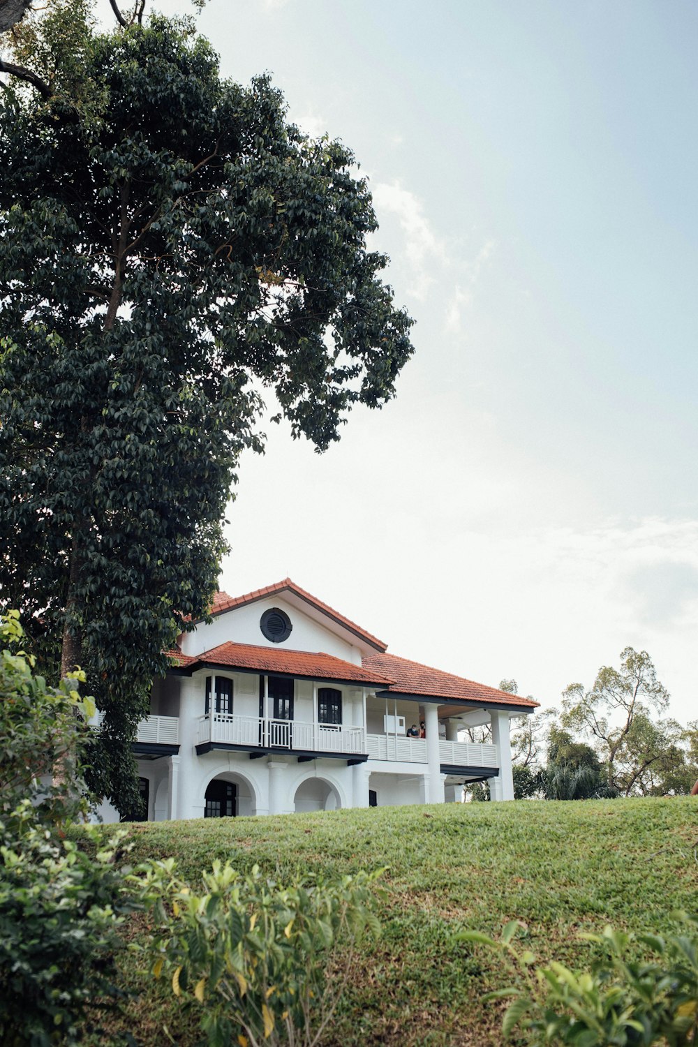 white and brown house near green tree under white clouds during daytime