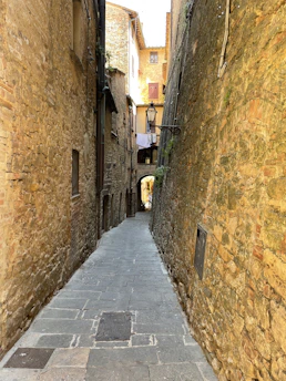 A narrow, sunlit alley winding through ancient stone houses in Grottole.