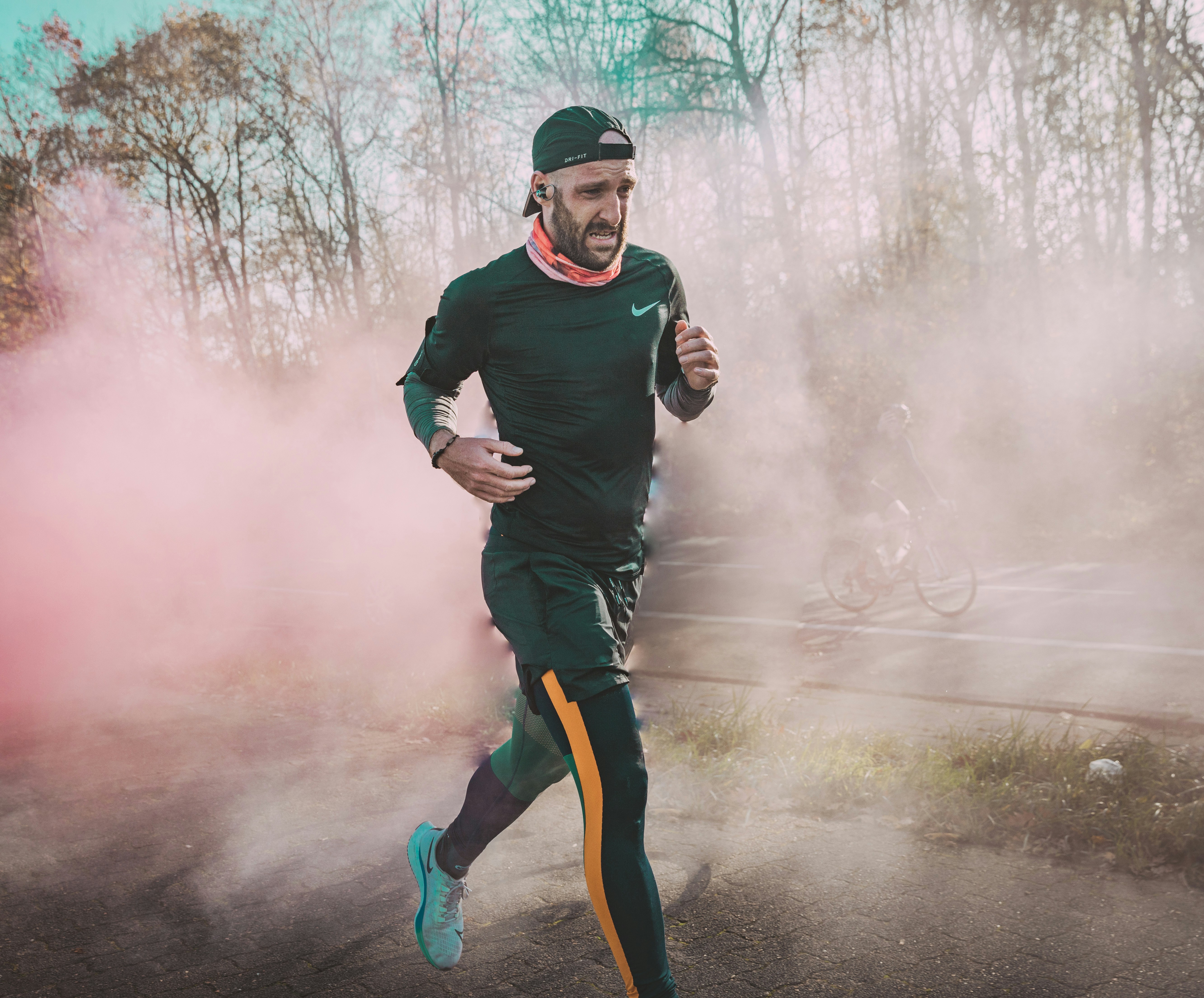 Man in black long sleeve shirt and green pants standing on road covered with white smoke