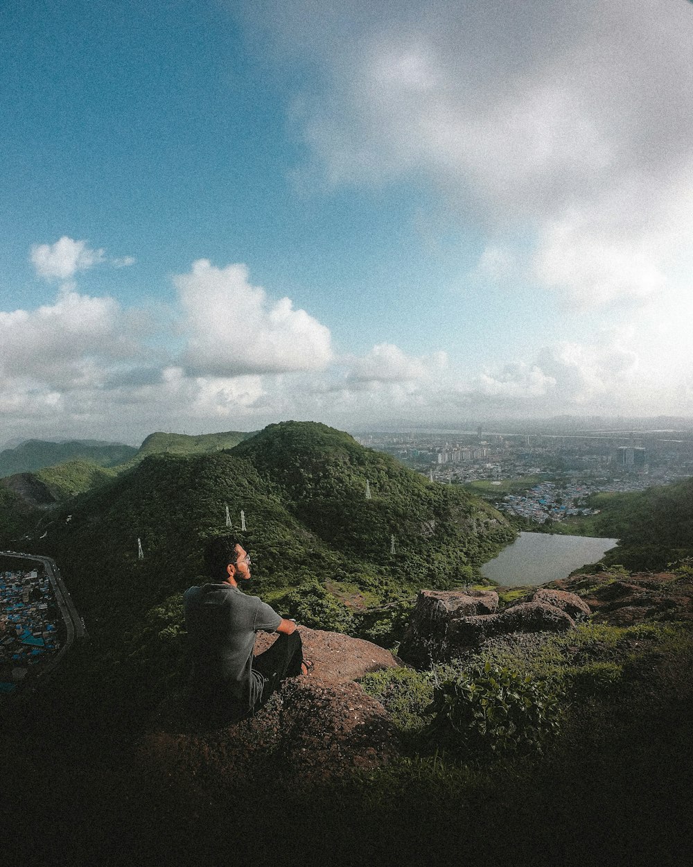person sitting on rock mountain during daytime