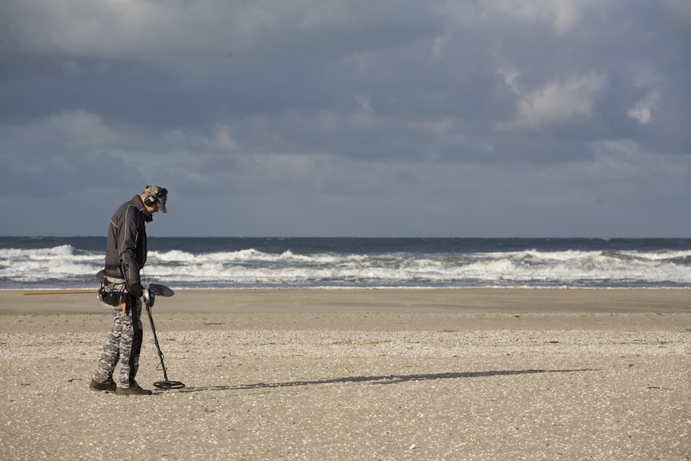 man in black jacket and black pants holding black dslr camera on beach during daytime