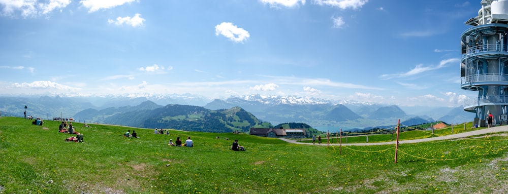 campo di erba verde vicino a montagne verdi sotto nuvole bianche e cielo blu durante il giorno