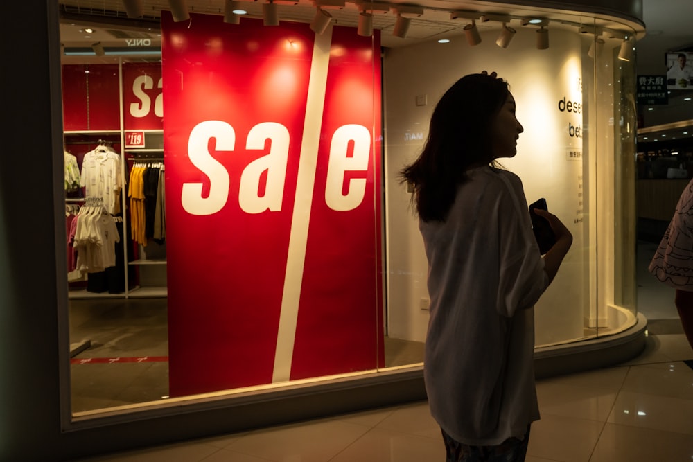 woman in gray coat standing near red and white stop sign