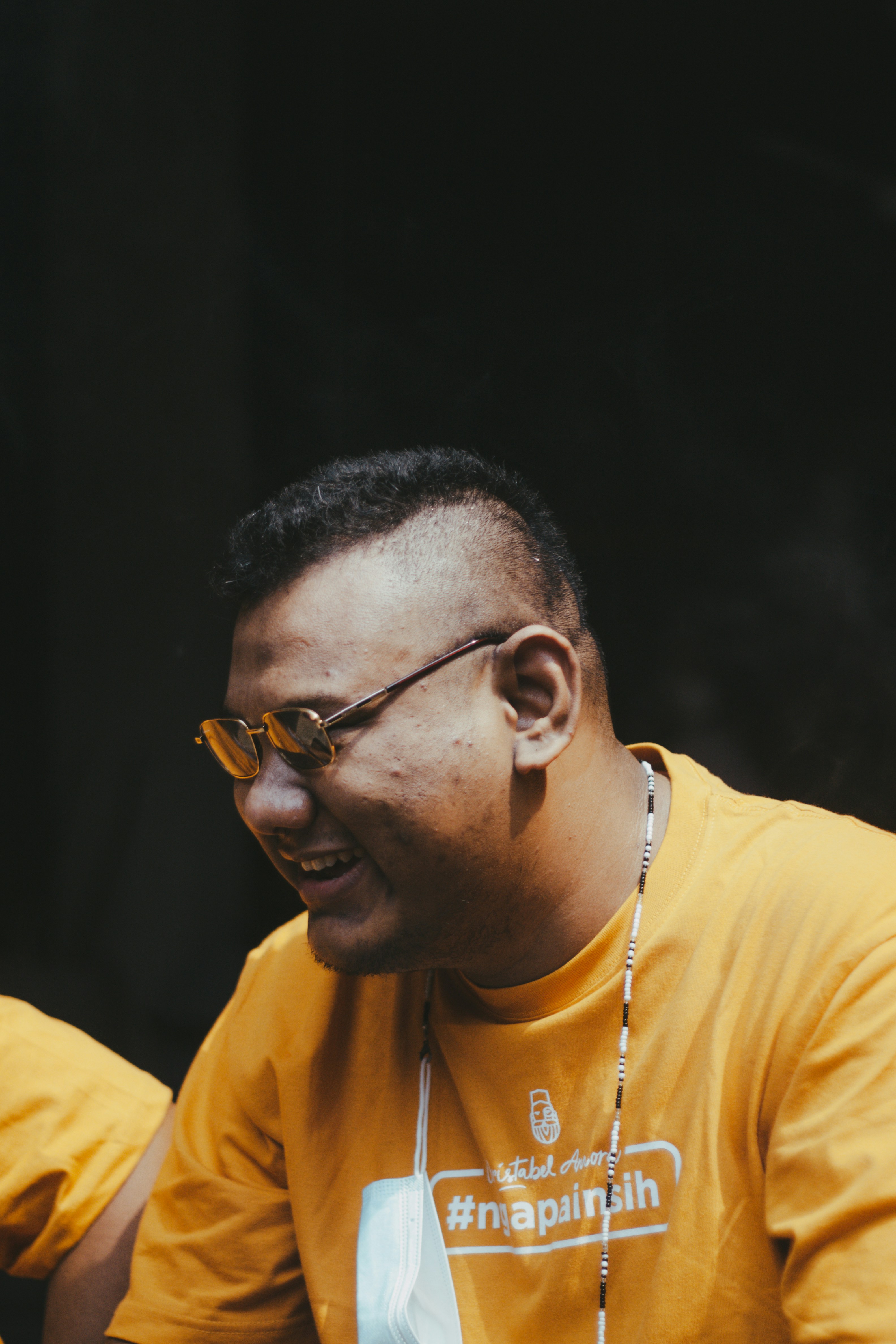 Pria dengan kemeja leher kru kuning mengenakan kacamata berbingkai hitam