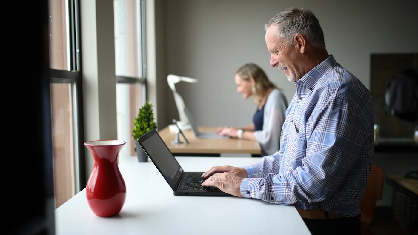 Older man working on a laptop at a desk at home