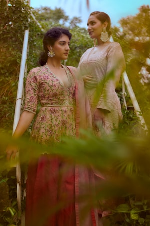 woman in red and brown floral dress standing on green grass during daytime