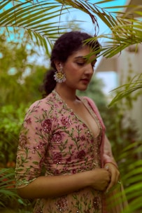 woman in red and white floral dress standing near green plant during daytime