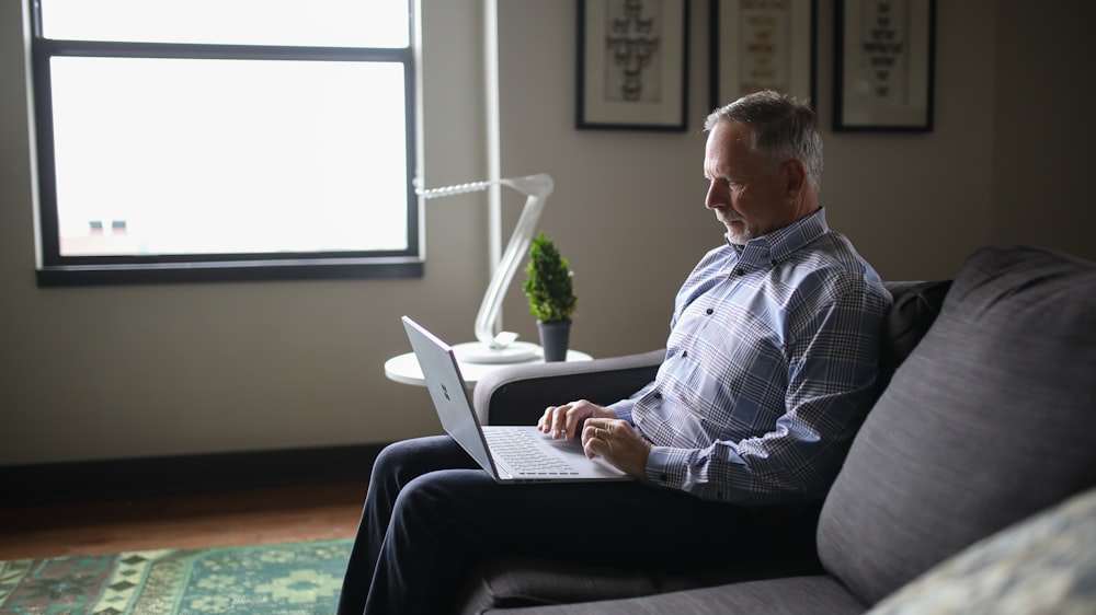 man in blue and white plaid dress shirt sitting on black couch