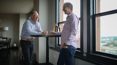 man in white dress shirt standing beside man in blue denim jeans