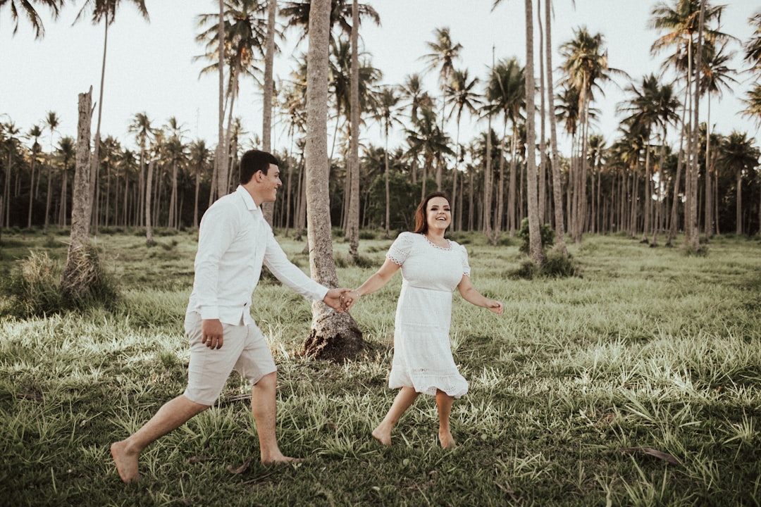 man and woman holding hands while walking on green grass field during daytime