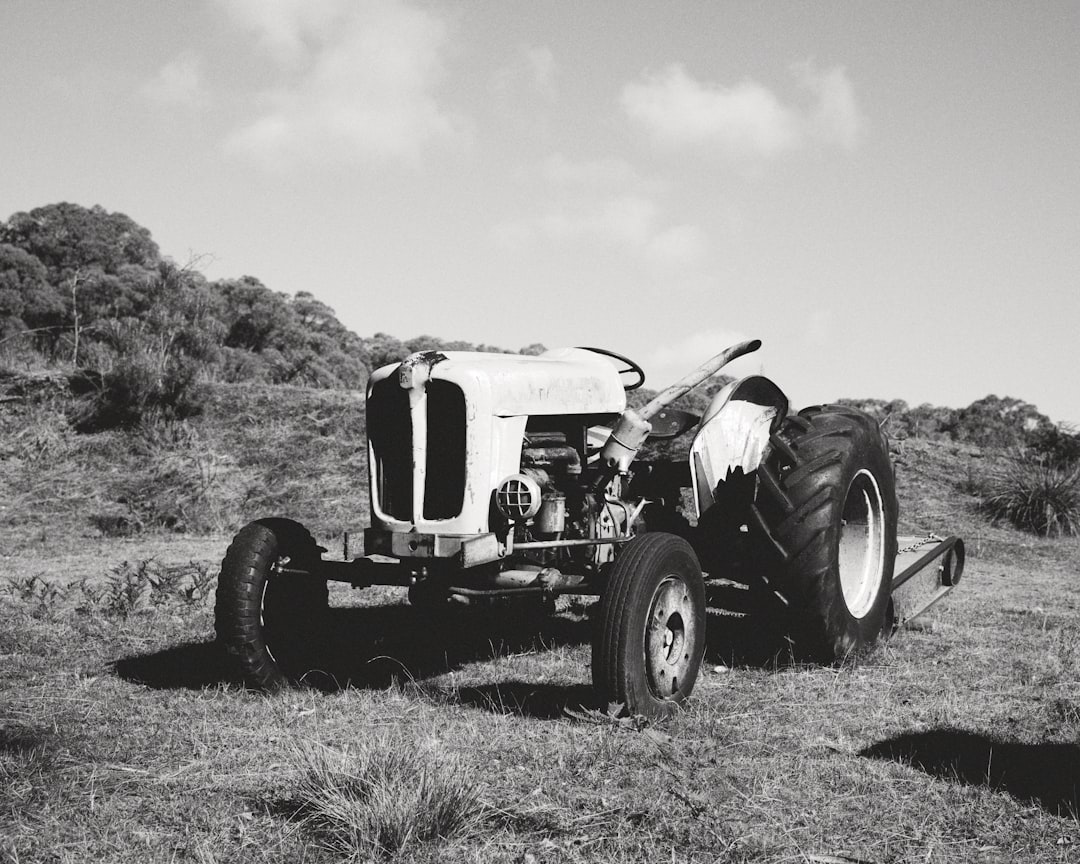 grayscale photo of tractor on grass field