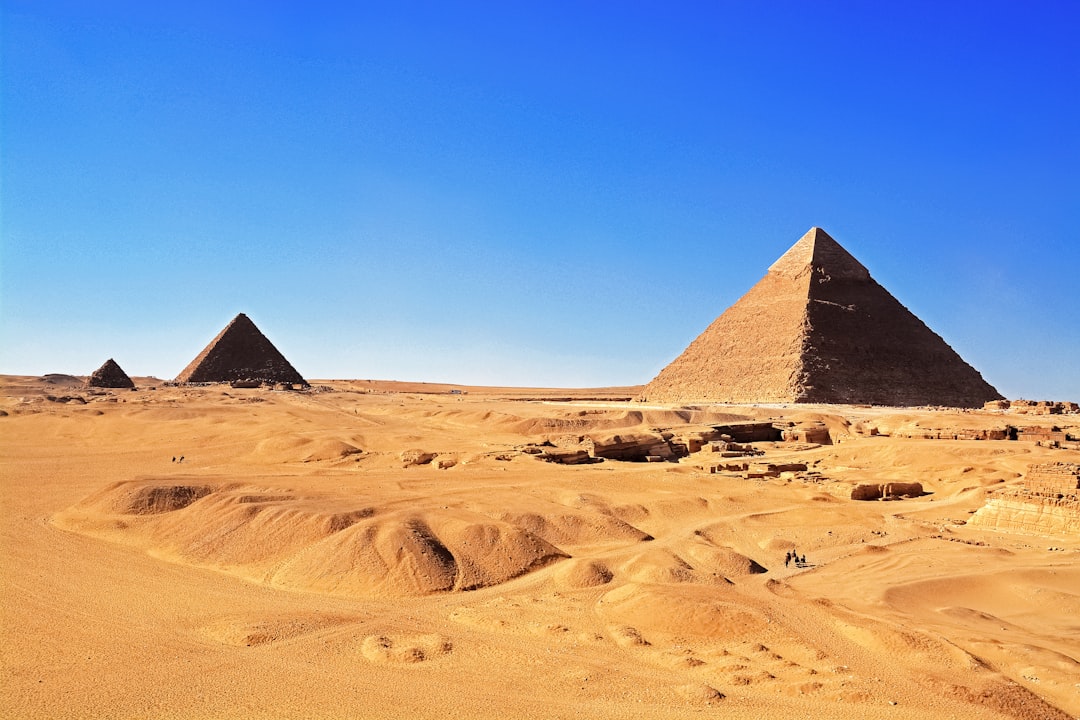 brown pyramid on brown sand under blue sky during daytime