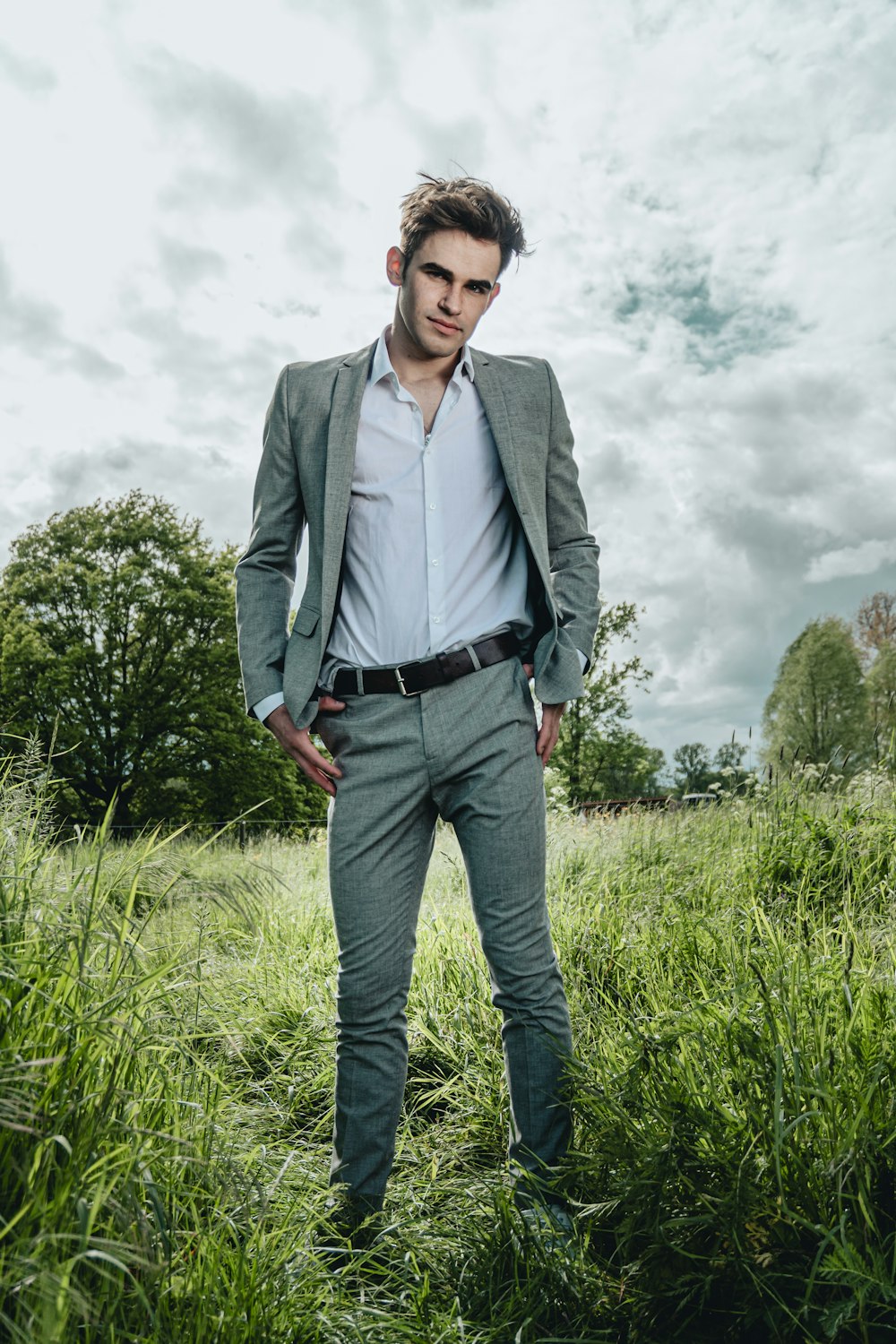 man in gray suit jacket standing on green grass field during daytime