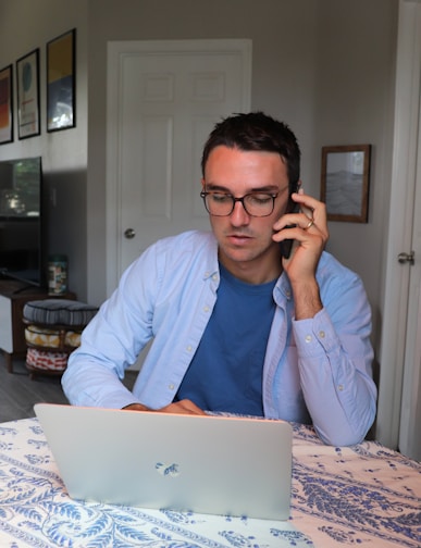 homme en chemise appelant un client en regardant son macbook