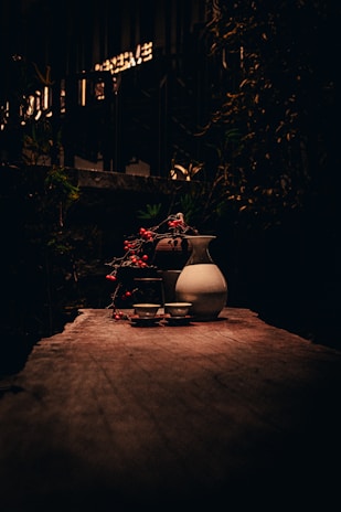 A rustic wooden table set with hand-painted ceramic plates and matching mugs, bathed in soft natural light.
