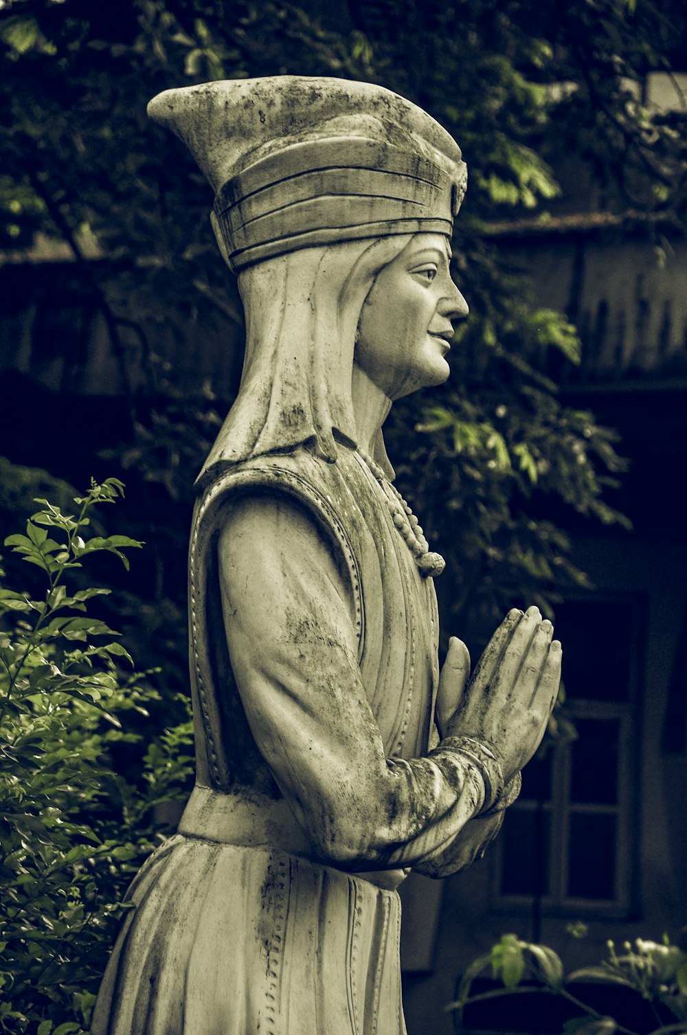 Statua di cemento grigio vicino a piante verdi