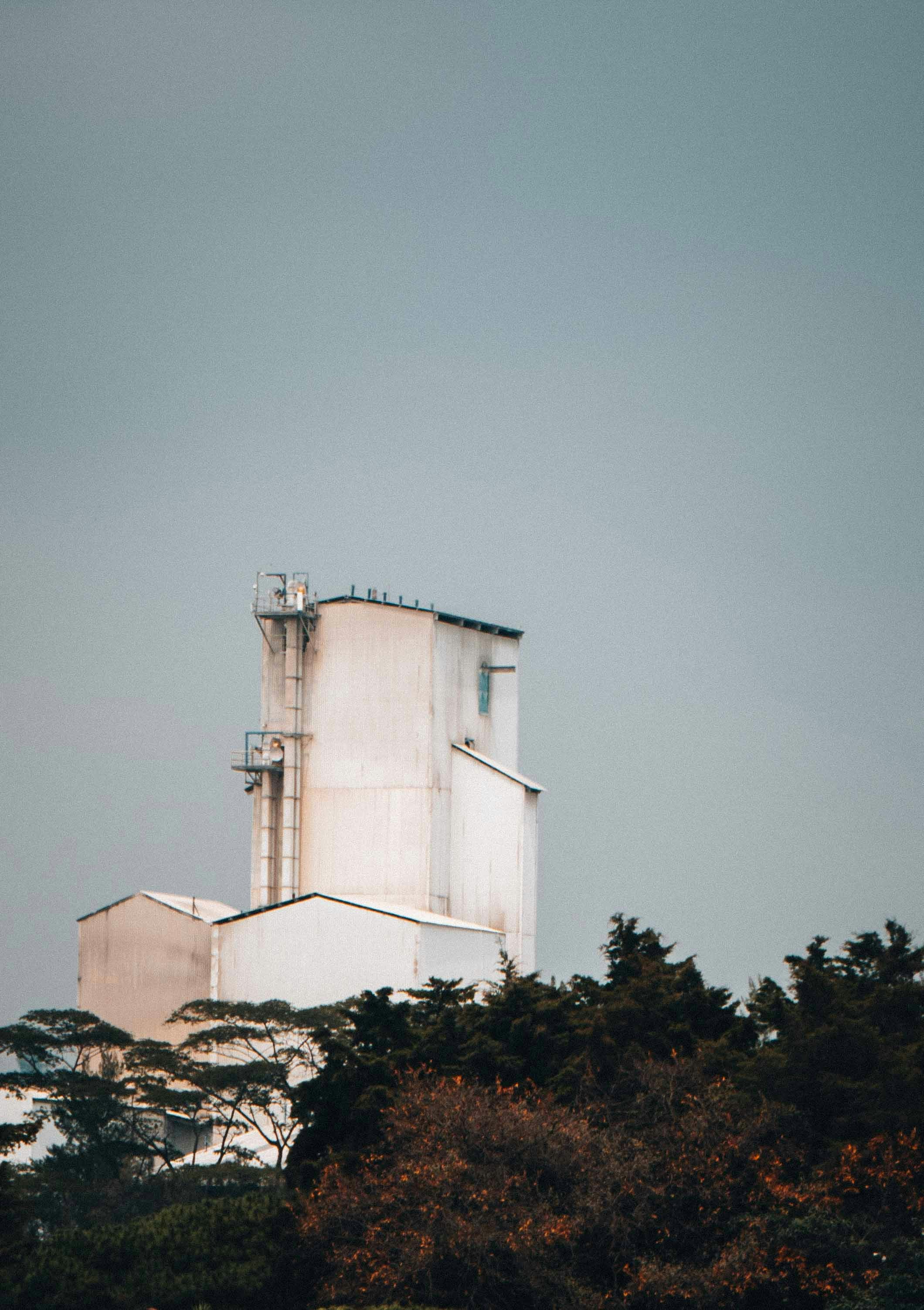 white concrete building near green trees under blue sky during daytime