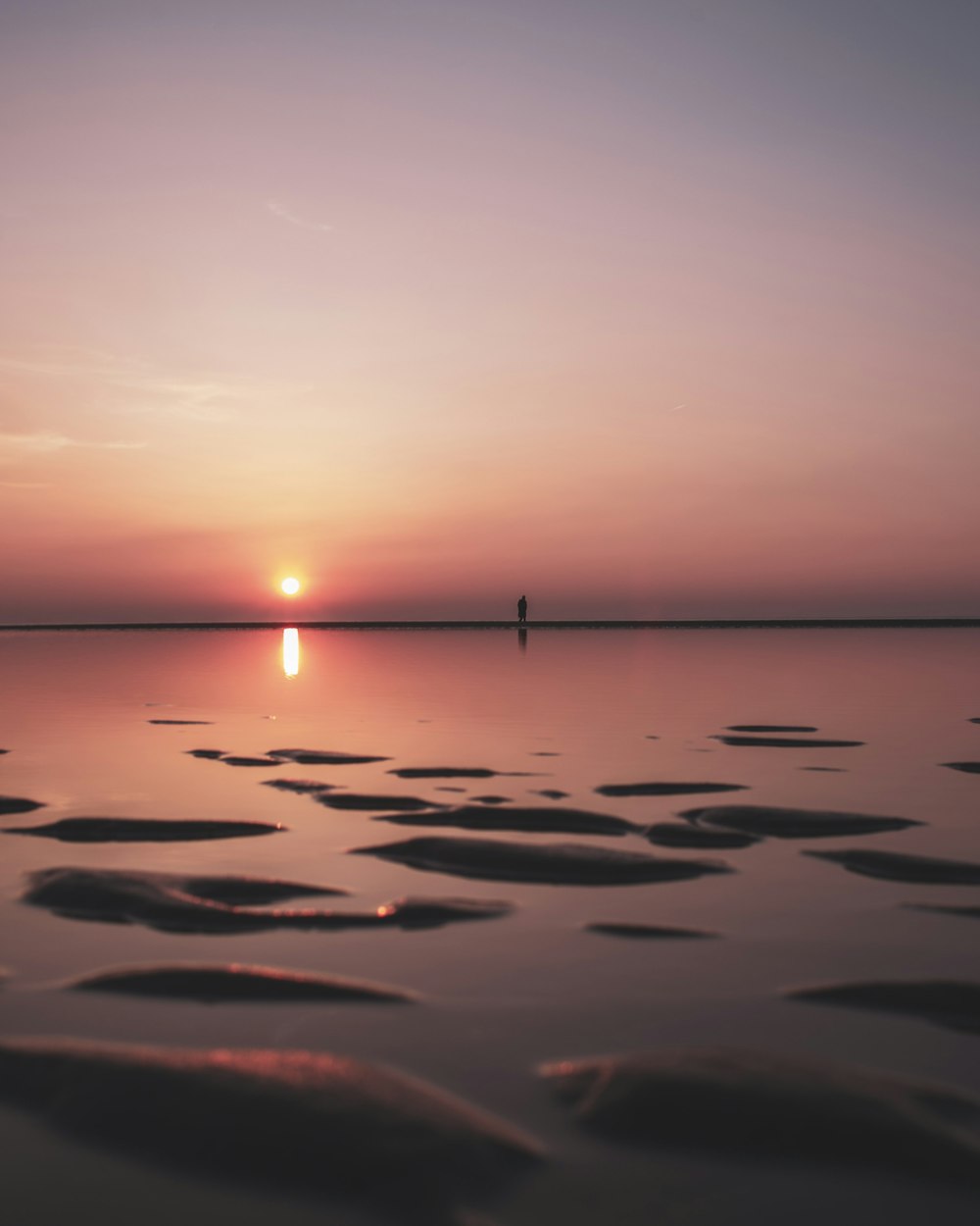 calm sea under gray sky during sunset