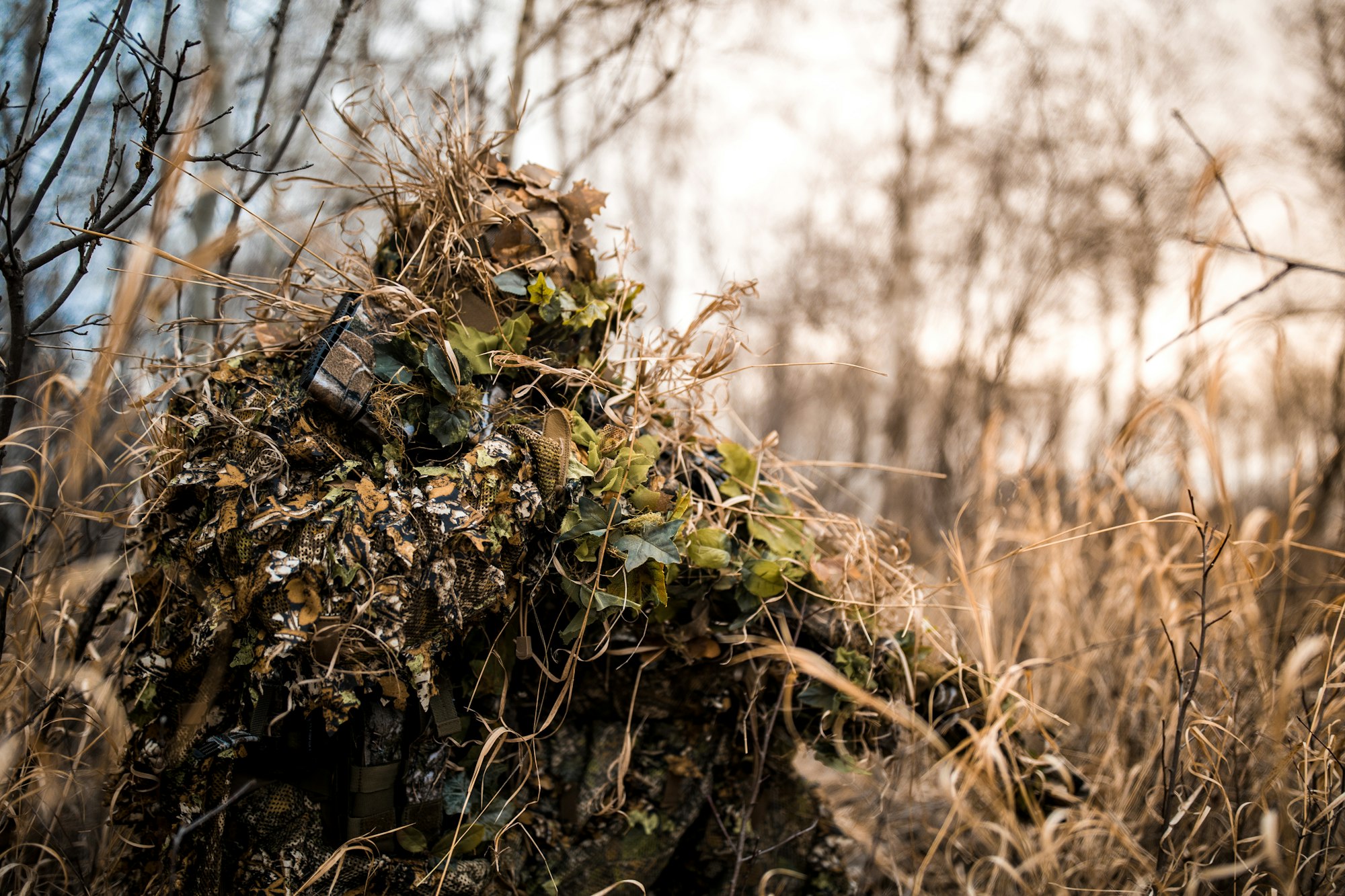 Hunter in a ghillie suit holding a gun