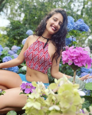 A smiling woman with a cane, surrounded by blooming flowers.
