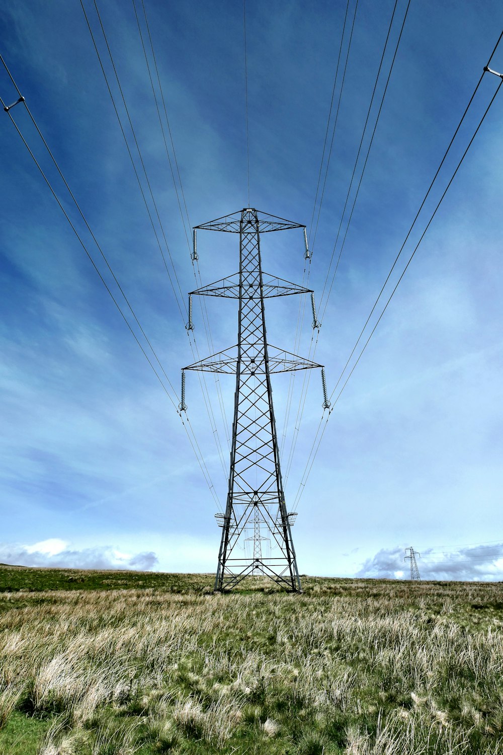 black electric tower under blue sky and white clouds during daytime