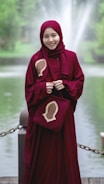 woman in red hijab standing near body of water during daytime